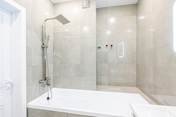 interior apartment Modern bathroom with sleek white vanity, illuminated mirror, and freestanding bathtub.  Neutral tones, marble-effect tiles