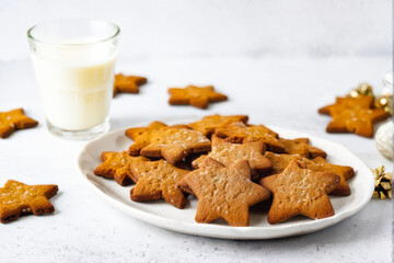 A plate of star-shaped gingerbread cookies paired with a glass of milk, perfect for festive holiday celebrations or cozy winter treats. Generative AI