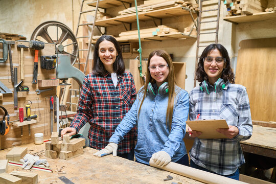 Young apprentices learning woodworking skills with experienced mentor in workshop
