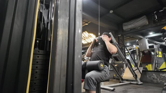 Handsome Man Performing Close-Grip Front Lat Pulldown on Gym Machine, Focusing on Back Muscles and Back Development During Workout,Side View