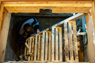 A man with construction tools performs engineering work in the basement of a house.