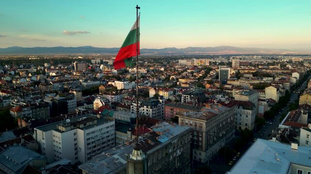 Aeriah helicopter footage of the bulgarian national flag atop of the National Assembly governmental building in Sofia the capitol of Bulgaria. Drone shot of European patriotism display in a city.
