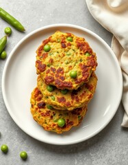 Three savory pea fritters rest on a white plate, a simple yet delicious meal