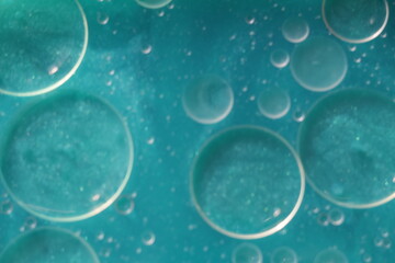 Una toma de cerca de varias burbujas de agua y aceite en movimiento en un fondo de color azul con desenfoque