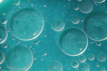 Una toma de cerca de varias burbujas de agua y aceite en movimiento en un fondo de color azul con...