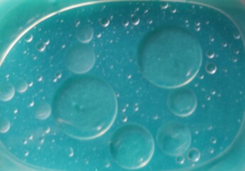 Una toma de cerca de varias burbujas de agua y aceite en movimiento en un fondo de color azul con...