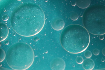Una toma de cerca de varias burbujas de agua y aceite en movimiento en un fondo de color azul con desenfoque