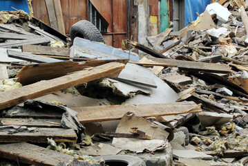 Pile of debris and rubble from a demolished building with an old tire and wooden planks. Ruined...
