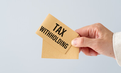 Tax Withholding Text on sticker in hand business woman on light background