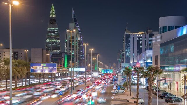 Cityscape aerial night timelapse of Riyadh, Saudi Arabia, featuring illuminated towers, skyscrapers, King Fahd Road and busy traffic. Palms and streetlights line the main highway through the city.