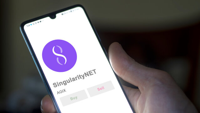 Close up on logo of AGIX SingularityNET on the screen of an exchange. AGIX SingularityNET price stocks, $AGIX on a device.