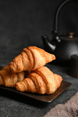 Three croissants placed on a black plate, photographed with a macro lens.