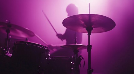 Silhouette of a drummer performing on stage in purple light.