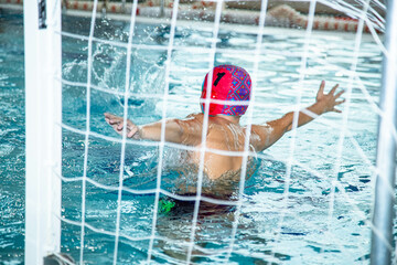 На фотографии изображены дети которые тренируются водным поло в большом и светлом бассейне. ворота