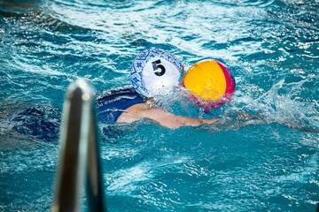 На фотографии изображены  как дети которые тренируются водным поло в большом и светлом бассейне.