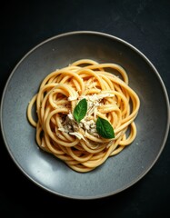 Delicious bucatini pasta with cheese and herbs served on a gray plate