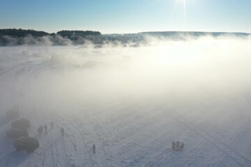 Early morning on the winter river fog and snowing many cars nearby