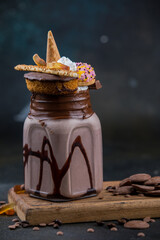 Indulgent chocolate milkshake topped with donuts, whipped cream, and candy in a mason jar. Perfect for dessert, sweets, and gourmet treat themes