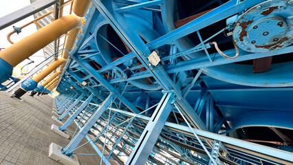 На фотографии современный вентилятор синего цвета с желтым цветом детали на нем  для охлаждения оборудование на открытом воздухе   .