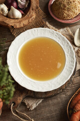 Chicken bone broth in white plate on a wooden table