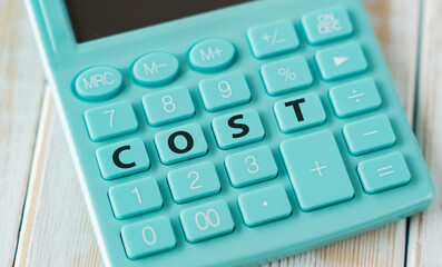 Cost text on calculator keyboard on wooden table, business concept.