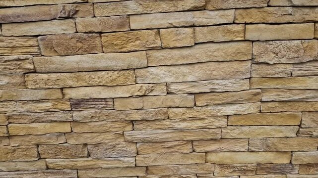 Modern gray brown, beige, metal door at the house lined with stone cladding. gutter for drainage of water on the pavement. limestone cladding