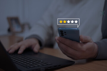 Close-up of a smartphone displaying a low star rating, symbolizing negative customer feedback, user...