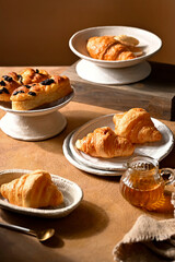 Cafe menu, breakfast. Fresh pastries: croissants, rolls, puffs and raisin bun with sour cream in plate and bowl.