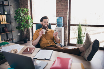 Full body photo of man eat chocolate device legs table wear yellow shirt formalwear comfortable...