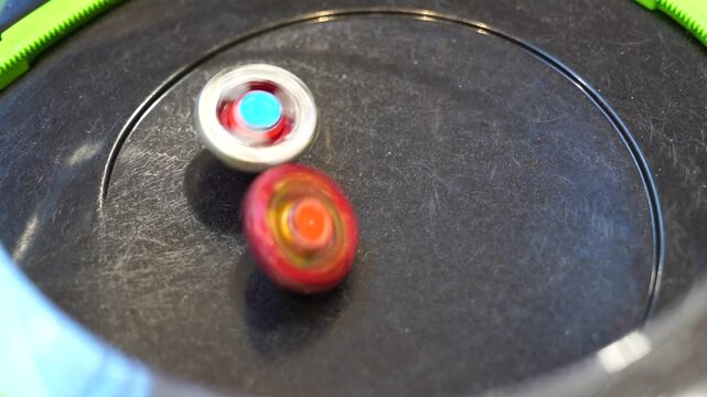 Popular and trendy boy beyblade spinning toy match and battle. Green elements of battle arena for beyblades in slow motion