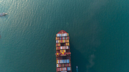 Aerial top view over international containers cargo ship at industrial import-export port prepare to load containers with big container loader ship vessel. global transportation and logistic business