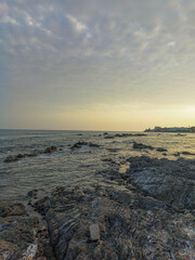 Obraz premium Rocky Beach in Málaga at Sunset with Calm Waves and Soft Sky