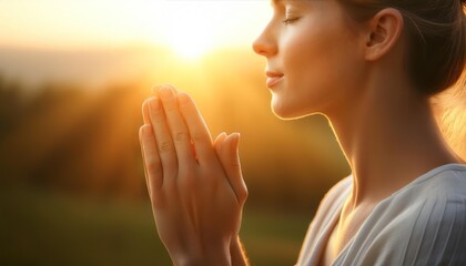 Person in meditation posture with hands clasped, golden sunset in background.
