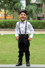 cute boy laughing out loud. Intense laughter of a 3.5 year old child. he is wearing formal cloths with bow tie and suspenders. He is having fun in the park in a day time. portrait of adorable child © Mrudang