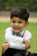 portrait of cute little 3 year old boy wearing bow tie, suspenders and white shirt and pants. Formal look of an adorable smiling boy.  Lovely and smart child with cute smile and in party mood at park.