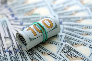 Roll of hundred dollar bills USD banknotes lies on big amount of united states money