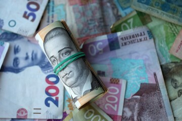 Roll of 500 Ukrainian Hryvnia money bills lies on big pile of ukrainian currency money close up