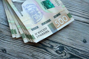 Many five hundred hryvnia money bills lies on wooden background. Ukrainian national currency close up