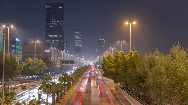 Aerial timelapse view of busy highway traffic on King Fahd Road with the iconic twisting skyscraper in Riyadh, Saudi Arabia. Illuminated streets and trees. Eighth-tallest twisting tower in the world.