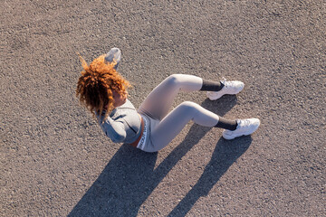 top view of determined woman in sportswear doing abdominal exercises on asphalt pavement, concept of urban sport and healthy lifestyle, copy space for text