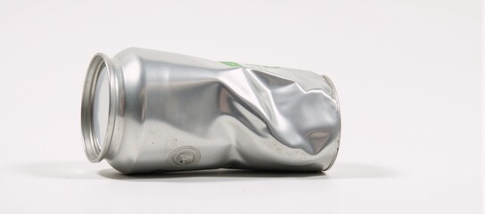 A crushed metal soda can against a white backdrop highlights wear recycling and sustainability