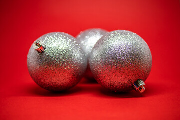 Sparkling silver Christmas ornaments on a vibrant red background