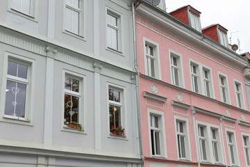 Obraz premium Two remarkable historical buildings in the city feature beautiful pastel facades, crafted windows, and vibrant flower boxes, adding unique charm and character to the urban landscape