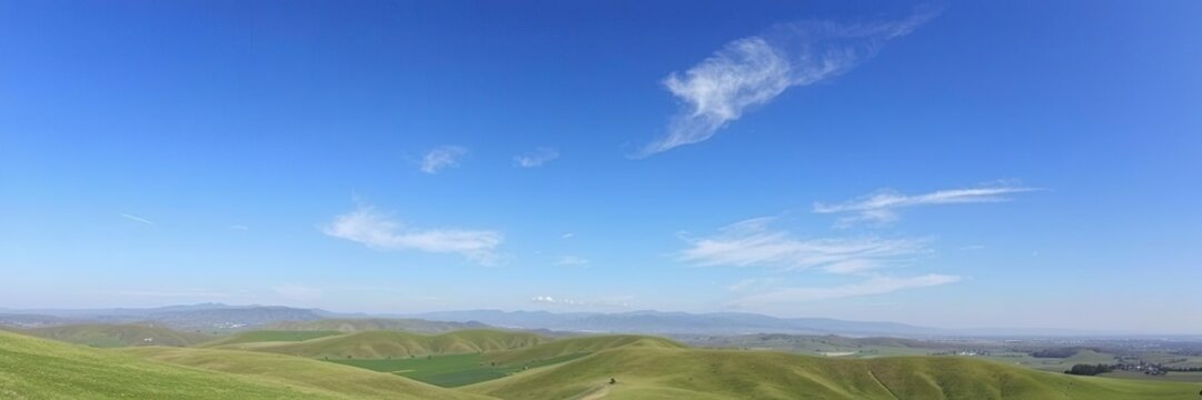 A serene landscape of rolling hills and distant mountains under a clear blue sky with a few wispy clouds drifting lazily across it, serene, atmospheric, peaceful