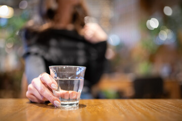 テーブルに置かれた水を手に取る女性