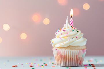 Cute pastel birthday cupcake with colorful sprinkles and a lit candle against a soft blurred background, perfect for celebration themes and festive occasions.