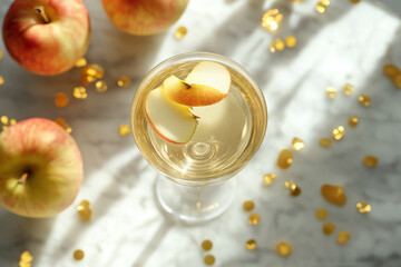 national apple cider day with a glass of golden apple cider surrounded by fresh red apples and festive golden glitter on a marble background