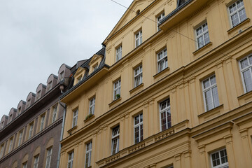 The elegant and eyecatching exterior of a yellow apartment building boasts intricate and decorative details, beautifully situated within a vibrant and dynamic cityscape full of charm and energy