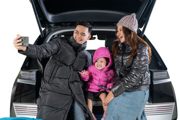 Family enjoying a joyful moment while taking a selfie in the back of an SUV during a winter outing