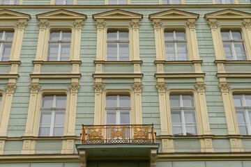 Fototapeta premium The facade of an old, historic building showcases a striking green paint job, embellished with intricate decorative windows, and features a lovely balcony that adds to its charm and character